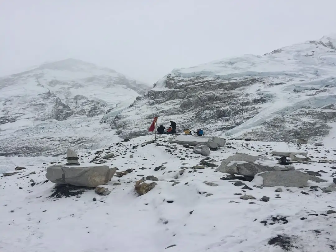 A trekker battling strong winds on a high-altitude pass showcases the unpredictable weather conditions that can pose challenges during the Everest Base Camp trek.